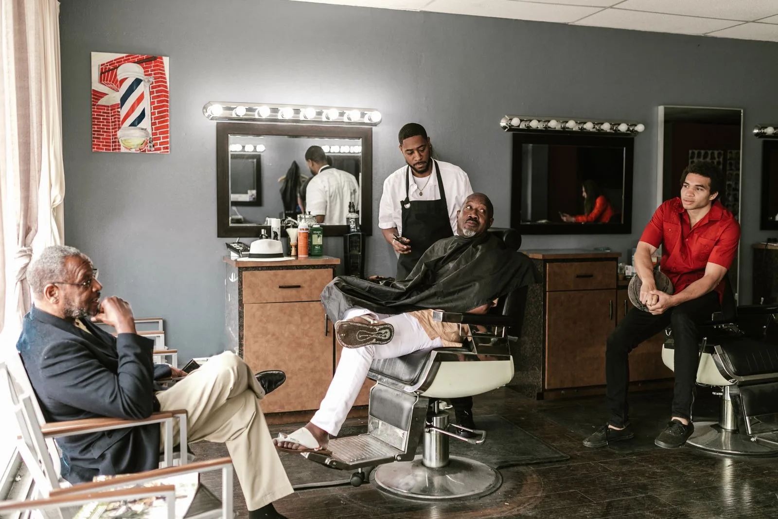 A busy barbershop in the middle of the day, clients waiting and a barber at work